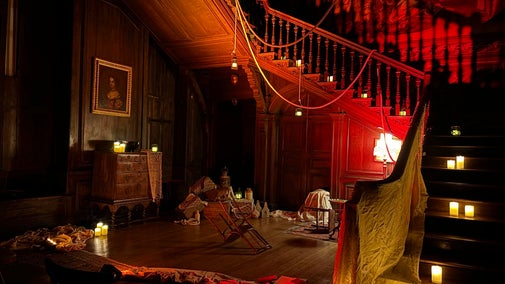 The Great Hall inside Hanbury Hall lit up with red light and set for a ghost story including candles, sheets, crates and old furniture